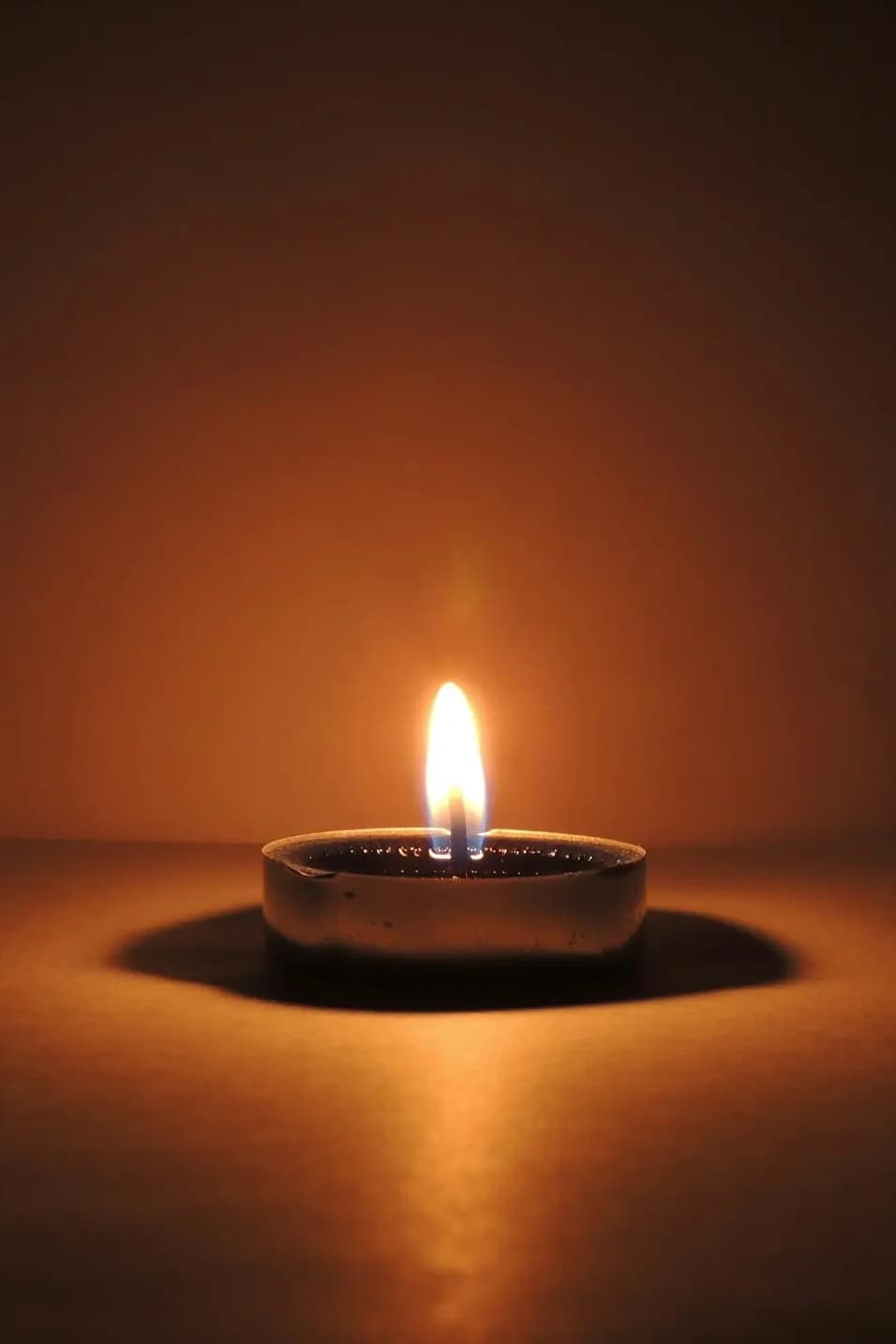 A single candle burning with a warm, steady flame against a dark background