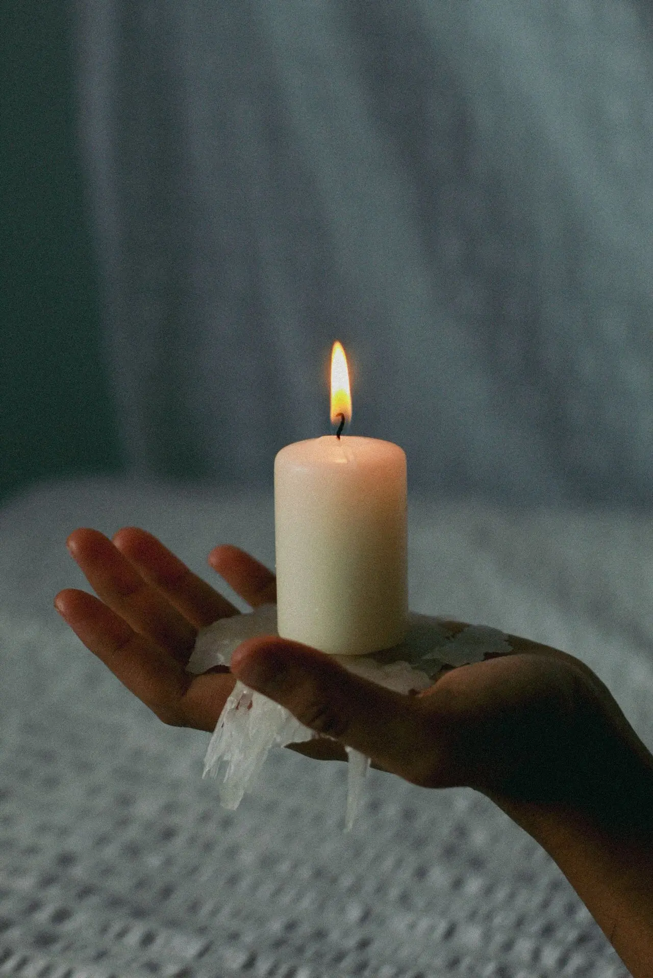 A single candle flame glowing warmly held in the palm of a hand